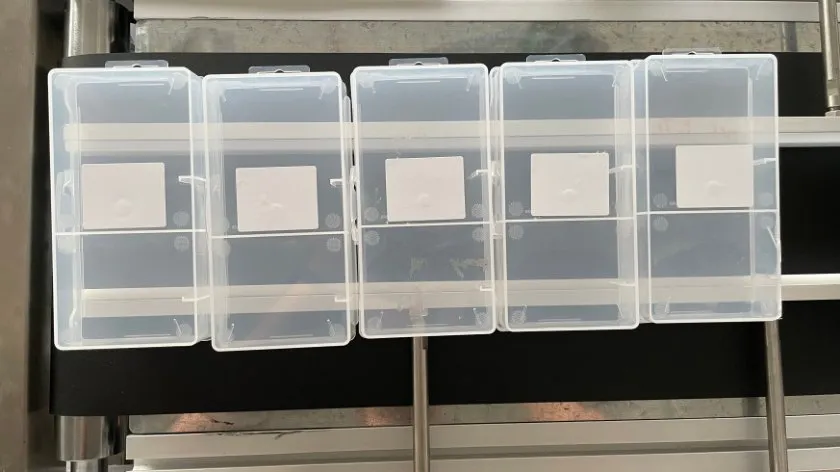 Automatic Bottom-Surface Labeling Machine — Clear plastic boxes labeled on the bottom