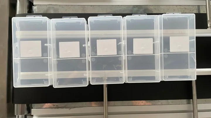 Automatic Bottom-Surface Labeling Machine — Clear plastic boxes labeled on the bottom